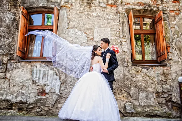 Happy luxury wedding couple is standing and kissing in the stree