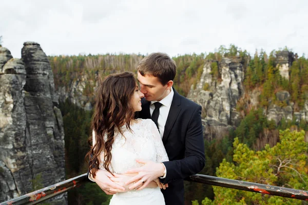 Wedding couple standing in the mountains against the sky. Cute romantic moment. Best day in the life of the bride.