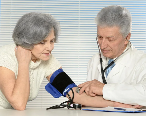 Elderly doctor measuring blood pressure