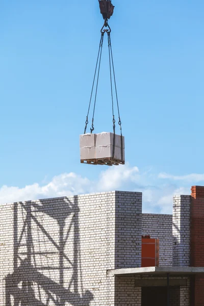 Heavy load hanging on construction site of brick building