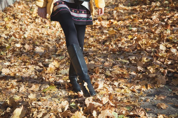 Shapely female legs walking on autumn yellow foliage