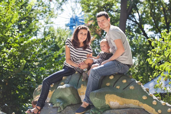 Young family with child in amusement park at summer day