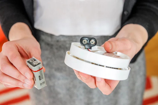 Woman installing 9 volt battery in smoke detector