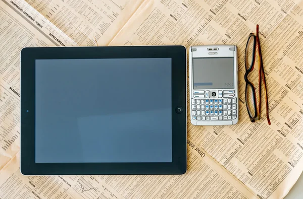 Modern Tablet and old QWERTY smartphone above the Financial Time