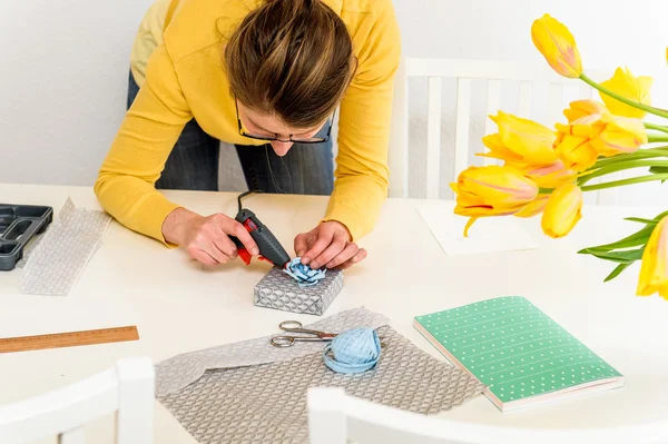 Woman working with glue pistol wrapping gift