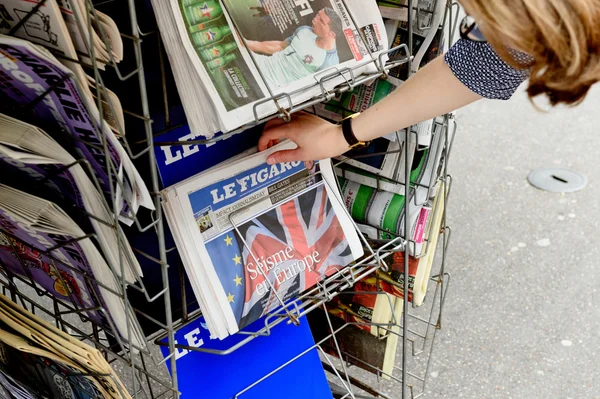 Woman buying Le Figaro newspaper with shocking headline about B
