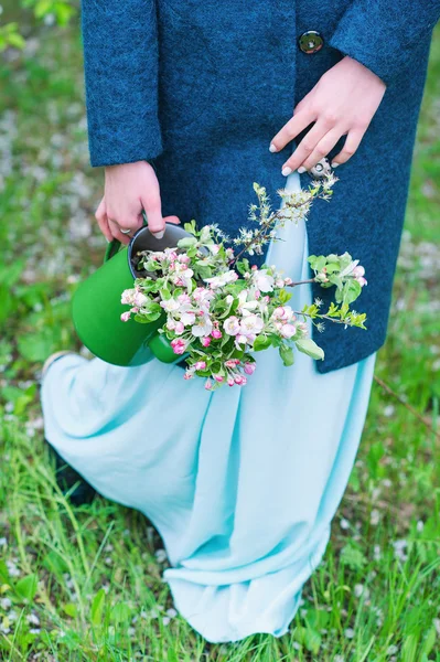 Woman carrying watering pot with blooming branches