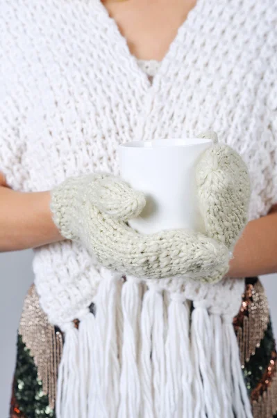 Woman hands in mittens holding cup