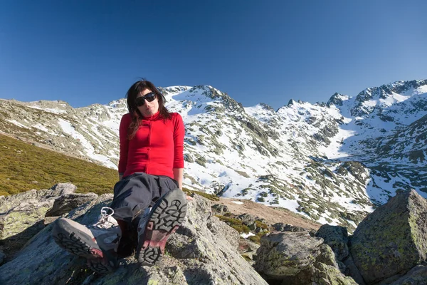 Red cardigan woman sitting posing on peak mountains