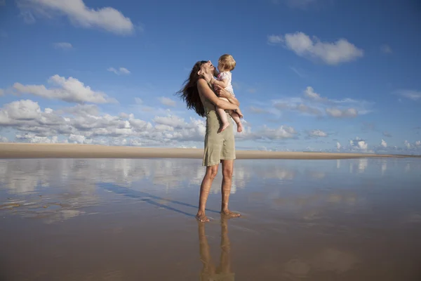 Laughing woman with baby at reflect beach