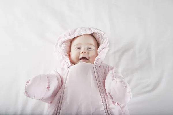 Smiling baby face wrapped in pink snowsuit