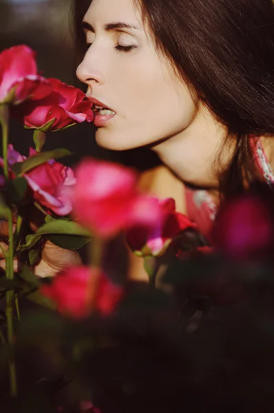 Beautiful girl smelling a rose in the garden