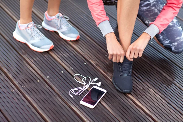 Girls tying running shoes laces.