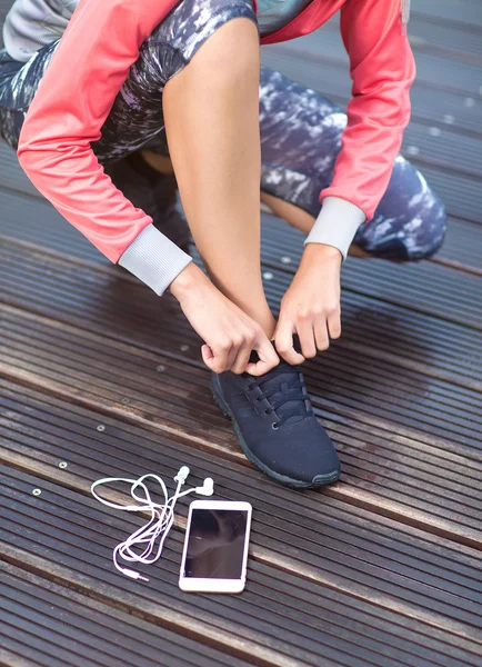 Girl tying running shoes laces.