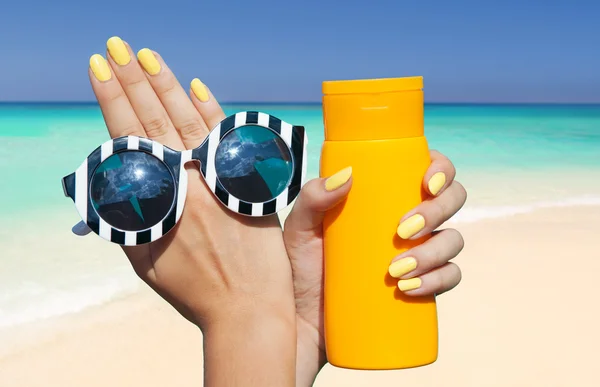 Woman at the pool holding sunglasses and sunscreen lotion