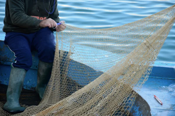 A fisherman repairing fishing net
