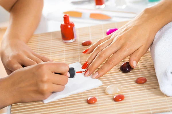 Woman in salon receiving manicure