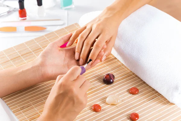 Woman in salon receiving manicure