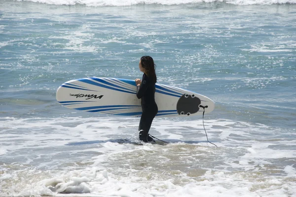 California Surfer Girl carrying her board in shallow water