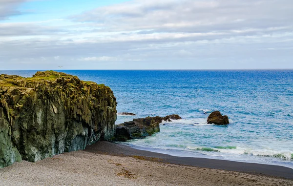 View of rocks at Black Beach and North Atlantic Ocean