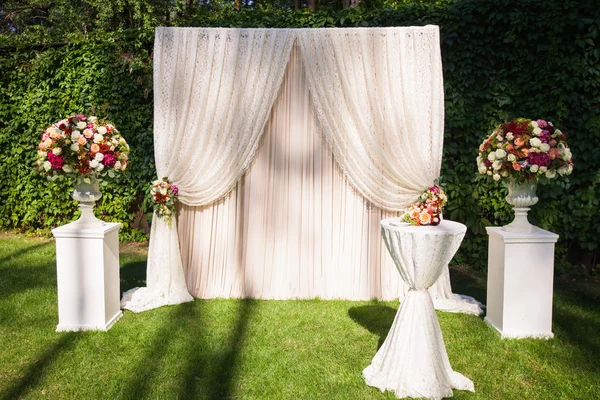 Wedding arch with big flower bouquets on the green leaves backgr