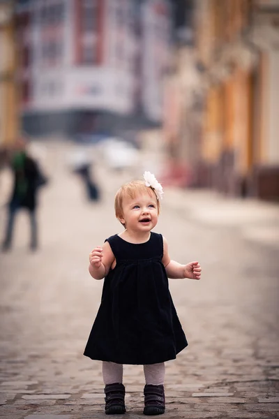 A little baby girl stands on the street