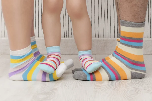 Mother, father and child wearing similar striped socks. Unrecognizable