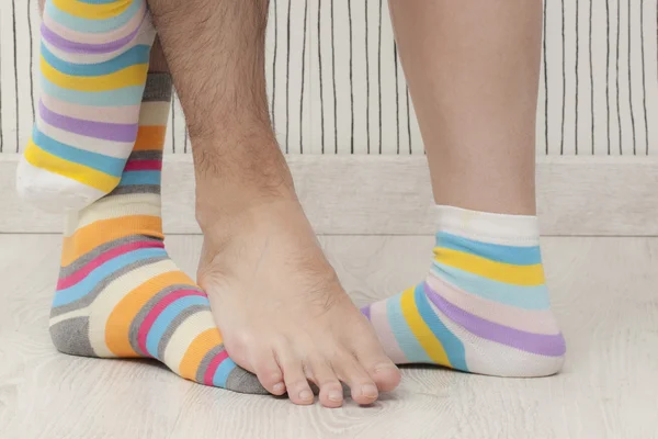 Man\'s and woman\'s feet in different socks. Unrecognizable