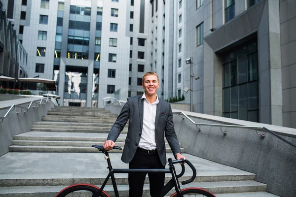 Businessman with the bike going up the stairs on the background of business centers