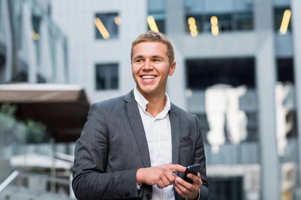 A young businessman standing on the steps of an office building, with a folder of papers and bike.Young handsome businessman talking on mobile phone