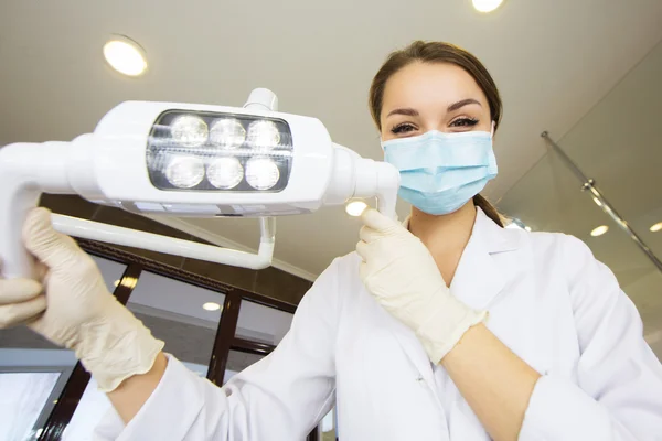 Young women dentist with sterile mask readily approaching a patient with dental instruments held in the hands protected with surgical gloves young dentist with sterile mask
