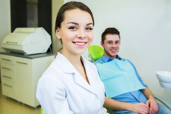 Dental surgeon and patient smiling happy after dental checkup, looking at camera.