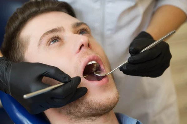 Close-up of male with open mouth during oral checkup at the dentist