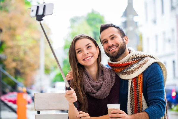 Close up - couple in the autumn park taking selfie with mobile phone. Smiling couple taking selfie with smart phone in the city park. Couple in the autumn garden. Couple taking selfie photo. love