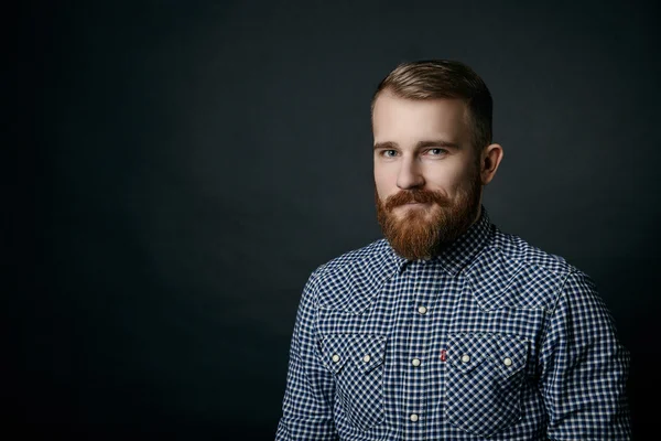 Smiling red bearded man studio portrait on dark background