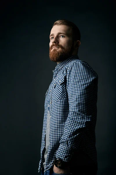 Pensive red bearded man studio portrait on dark background