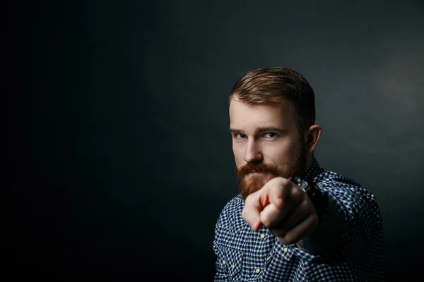 Red bearded man pointing studio portrait on dark background