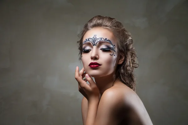 Sensual woman with face art and red lips looking down