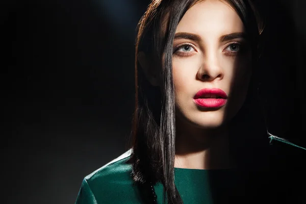 Close-up of black-haired woman with half face in shadow