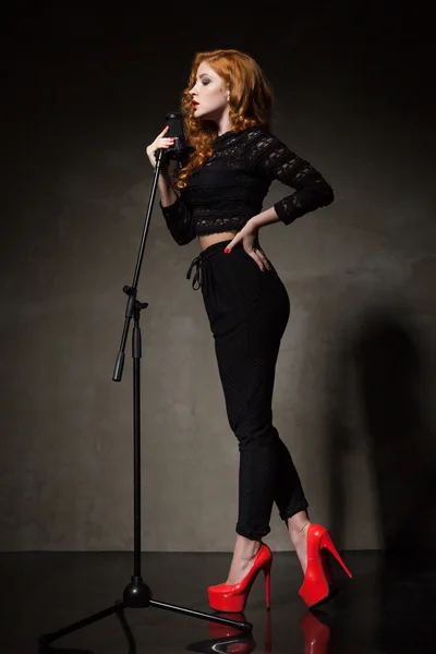 Portrait of beautiful singer in red heels and black clothes