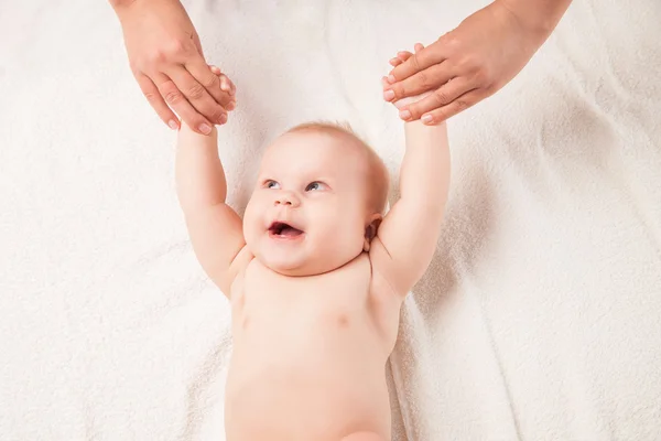 Cute baby lying on white blanket hands lifted