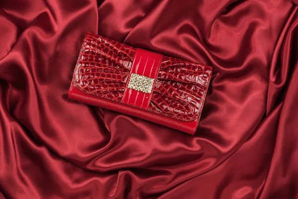 Red lacquer bag inlaid with diamonds lying on a red silk