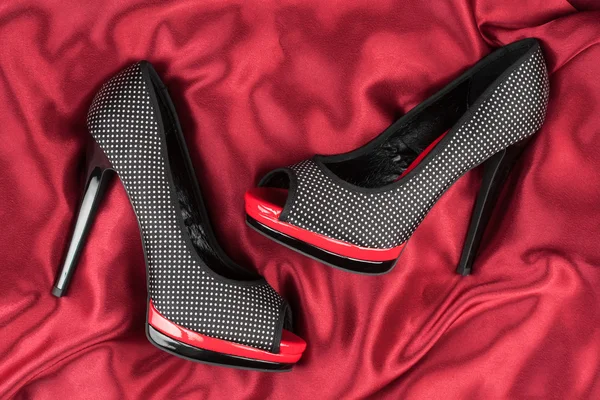 High-heeled shoes lying on red fabric