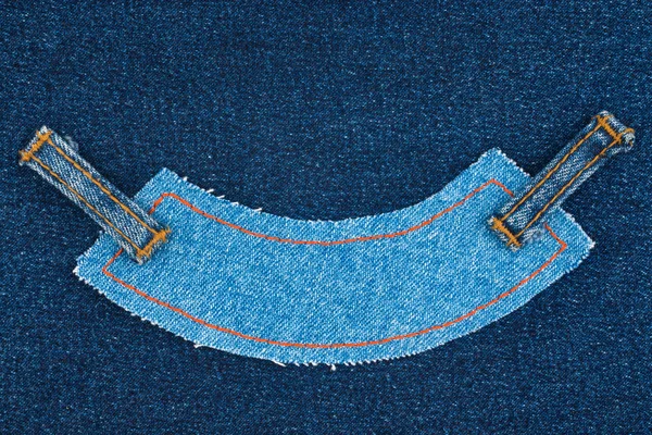 Blue denim jeans tag label lying on dark jeans.