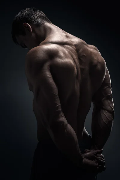 Handsome muscular bodybuilder posing over black background