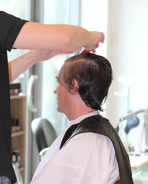 A man cuts hair in a barbershop. Master young stylist.Focus on grey hair