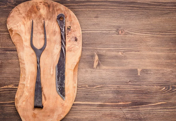 Knife and fork on cutting board from left of table