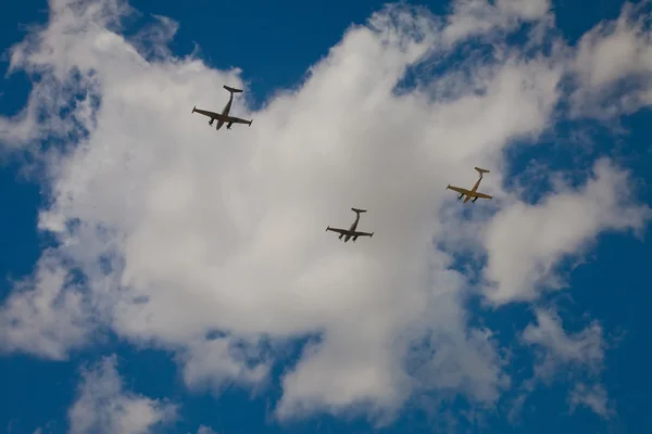 Silhouettes of three Beechcraft airplanes in deep blue sky