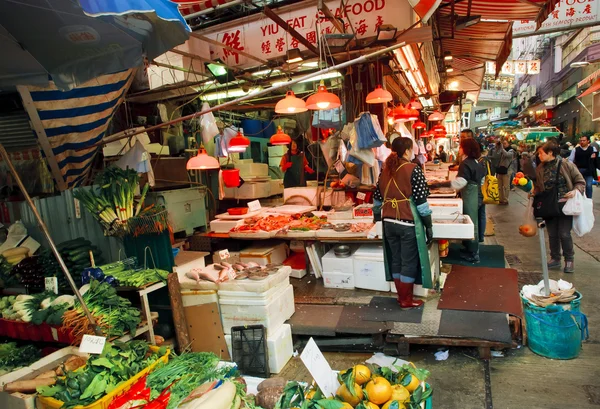 Customers of outdoor market choose seafood, fruits and vegetables on busy narrow street