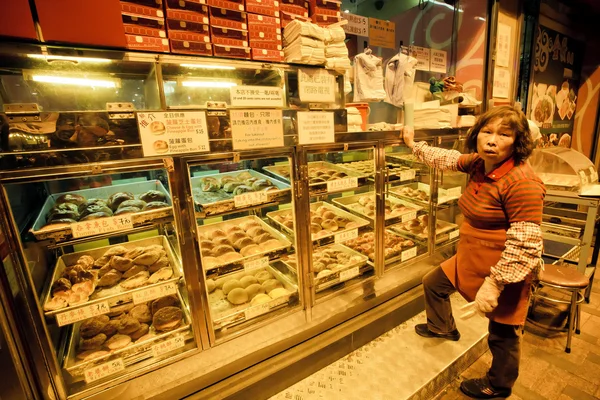 Elderly female seller of street bakery with cakes and buns for a late dinner